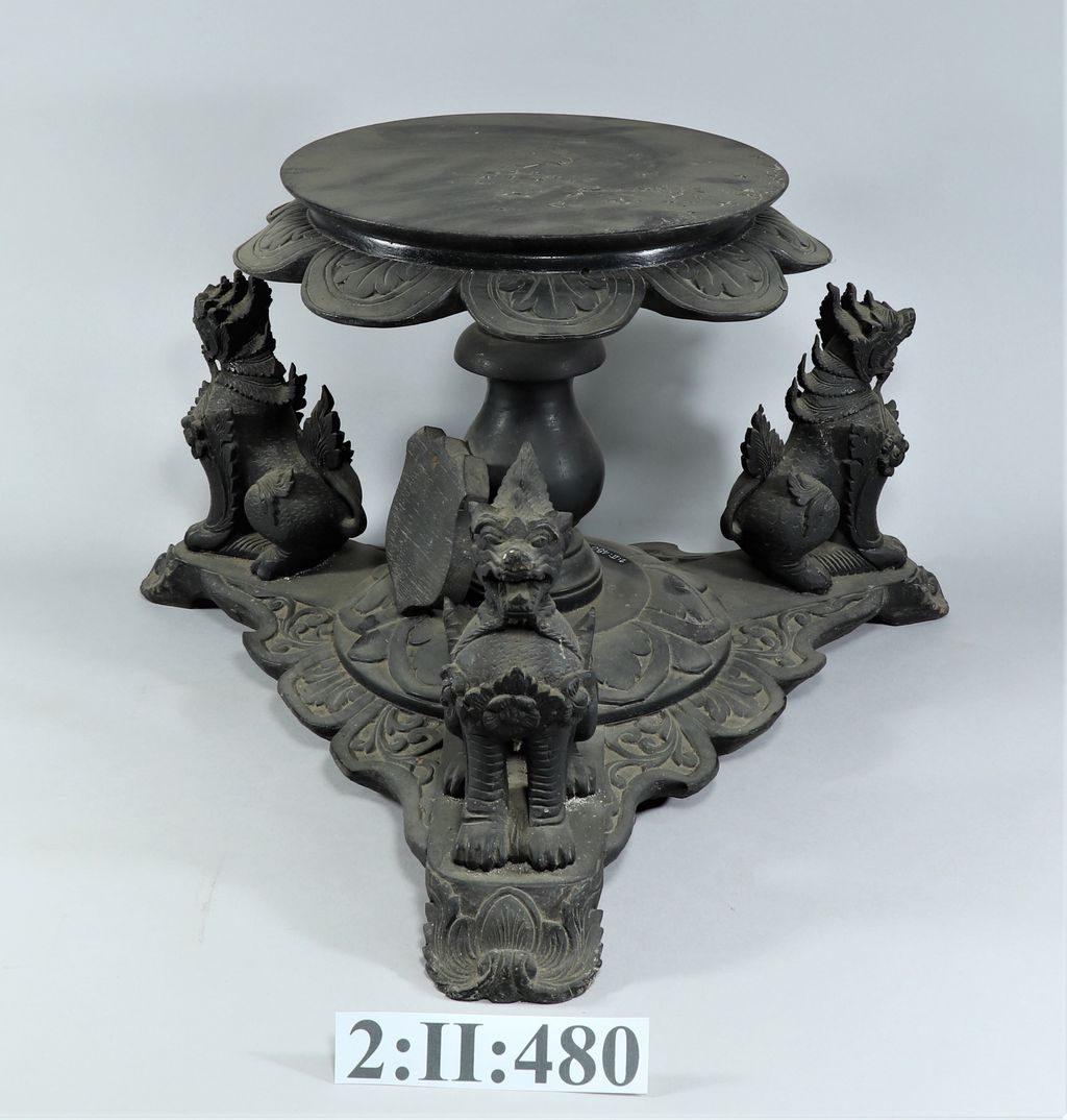 ໂຕະນ້ອຍເຮັດດ້ວຍໄມ້ ມີລາຊາສີ 3 ໂຕຢູ່ຕີນ.