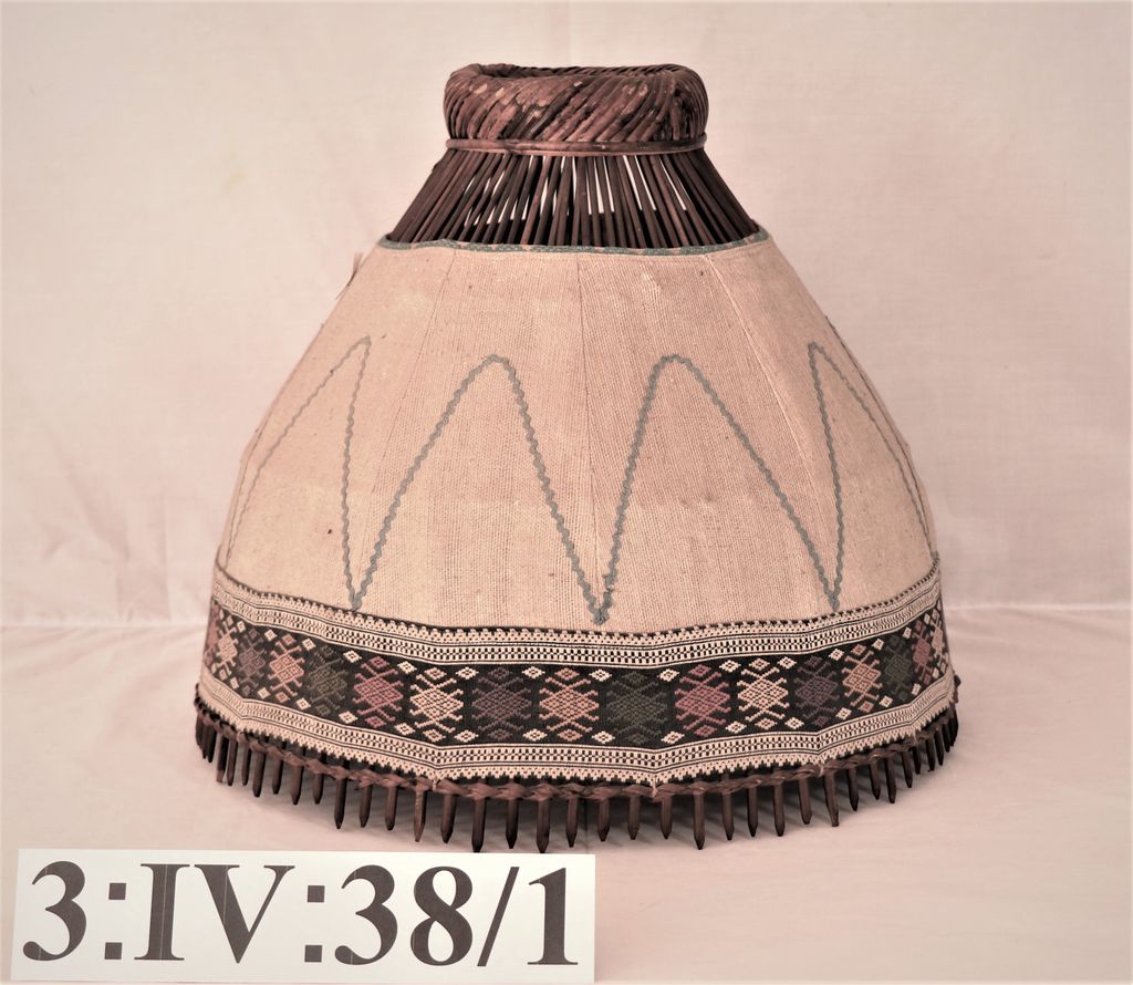 ໂຄມໄຟ ເຮັດດ້ວບໄມ້ ຫຸ້ມດ້ວຍຜ້າຝ້າຍ ສີຂາວ ຕີນຜ້າຕໍ່າເປັນລາຍ ( ອັນງອມໂຄມ ).