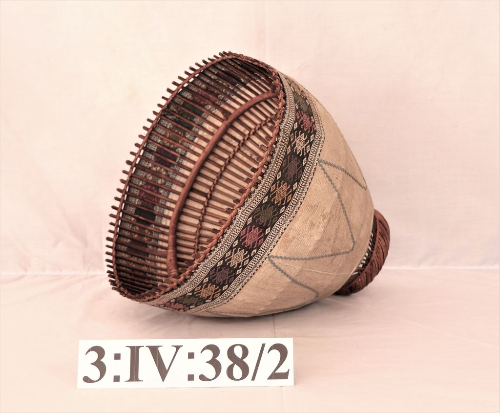 ໂຄມໄຟ ເຮັດດ້ວບໄມ້ ຫຸ້ມດ້ວຍຜ້າຝ້າຍ ສີຂາວ ຕີນຜ້າຕໍ່າເປັນລາຍ ( ອັນງອມໂຄມ ).