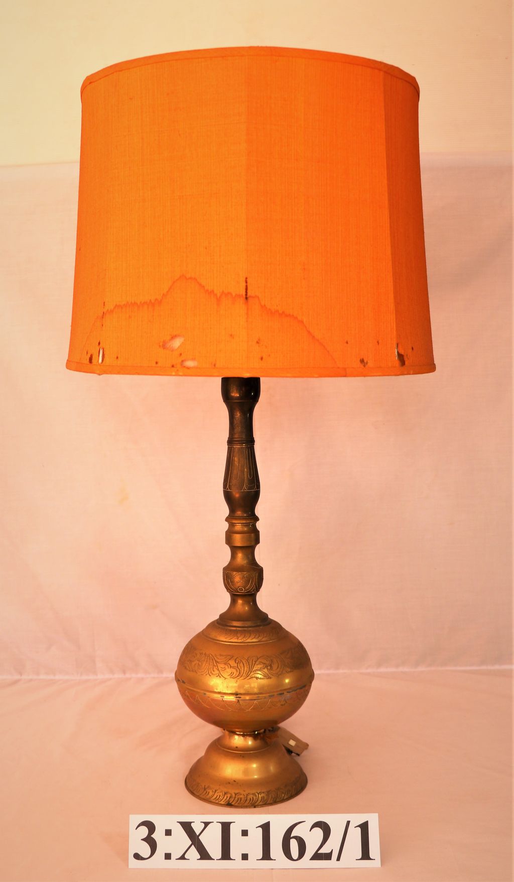 ໂຄມໄຟ ເຮັດດ້ວຍທອງ ຜ້າໂຄມ ເຮັດດ້ວຍຜ້າສີແສດ.