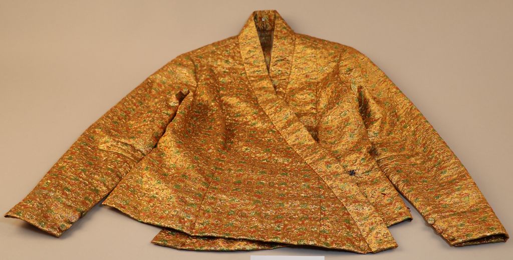 ເສື້ອຄໍປ້າຍ ຜ້າໄໝ ສີທອງ ລາຍດອກສີຂຽວປົນສີສົ້ມ.