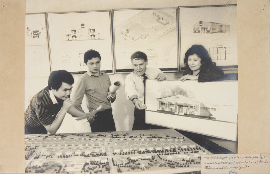 ນັກສະຖາປະນິດຂອງສະຖາບັນ ກາສກຣາສດັນເຊລສະໂຕຍ ພ້ອມກັນພິຈາລະນາເບິ່ງແຜນຜັງບ້ານໜຶ່ງທີ່ຈະສ້າງຂື້ນໃນຂອບເຂດນິຄົມກະເສດ ນູລະລື ປີ 1984