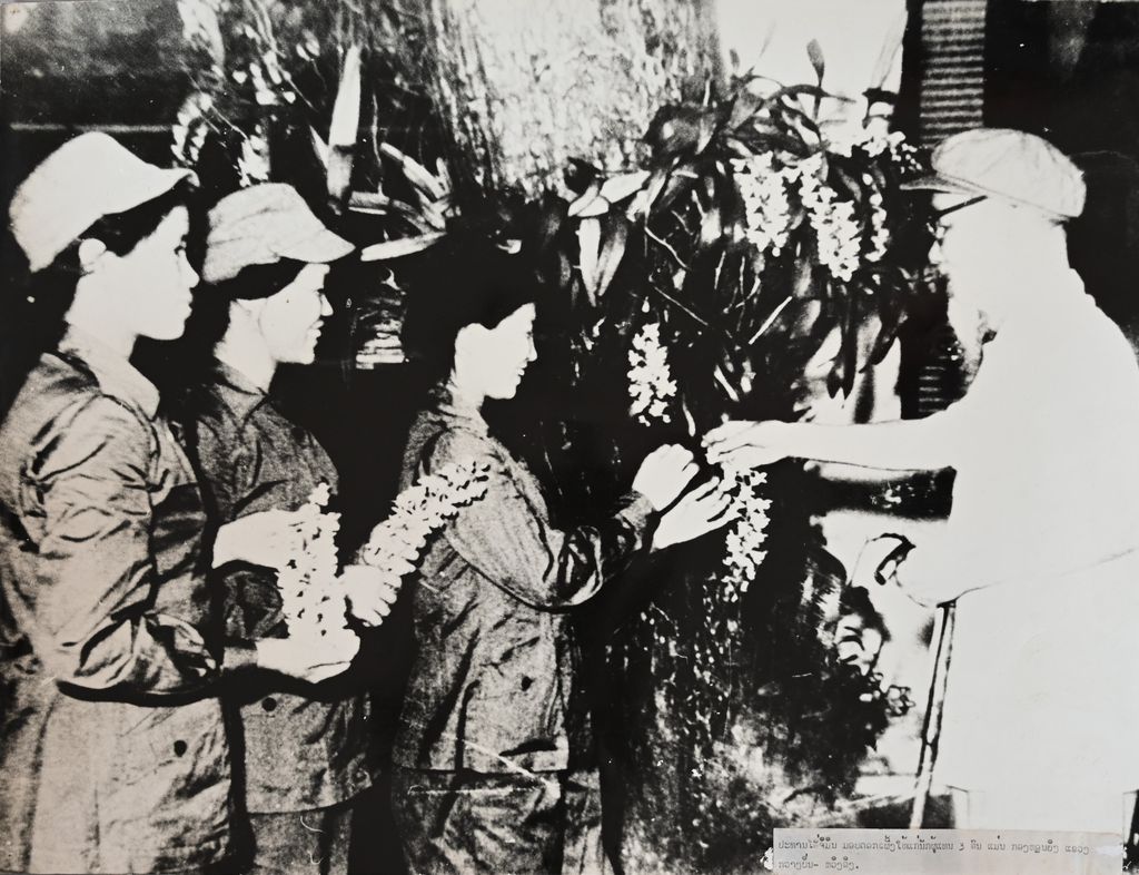 ປະທານ ໂຮຈິມິນ ມອບດອກເພີງໃຫ້ແກ່ຜູ້ແທ່ນ 3 ຄົນແມ່ນກອງຫຼອນຍິງ