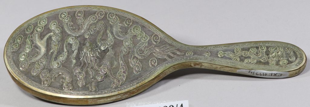 ແວ່ນເຮັດດ້ວຍແກ້ວ ໂອບດ້ວຍເງິນດ້ານຫຼັງເປັນຮູບໂຕມັງກອນ.