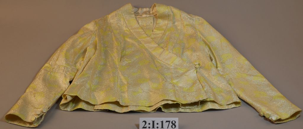 ເສື້ອຄໍປ້າຍ ຜ້າໄໝລາຍດອກສີງາຊ້າງ ລາຍດອກສີເຫືຼອງຂີ້ມິ້ນ.